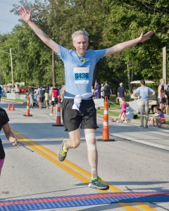 Runner John Cunningham jumps for joy as he crosses the finish line.