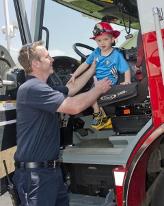 Firefighter Mathias Burke helps a little visitor down from a fire truck cab.